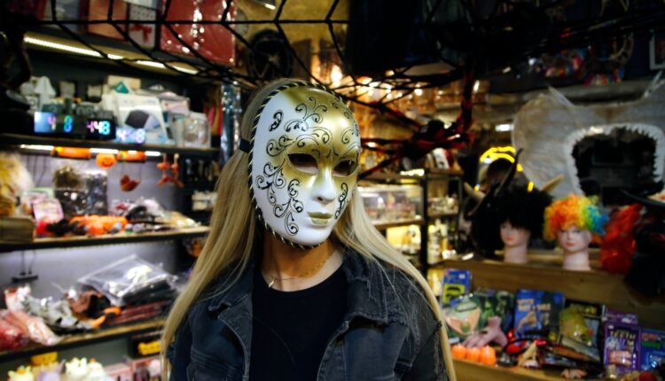 Woman wearing a white and gold Halloween mask in a Tehran costume shop